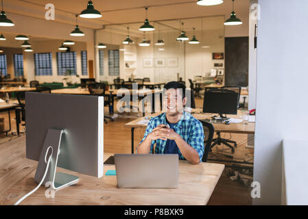 Smiling young designer working at his desk in an office Stock Photo