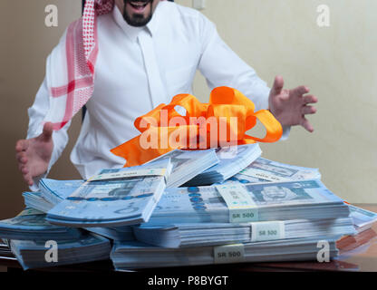 Saudi Arab man surprized with stacks of money on the side table at home Stock Photo