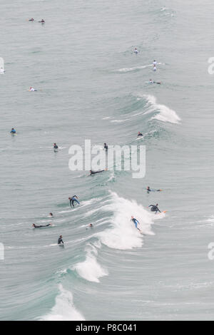 Surfers hoping to ride waves on the Atlantic ocean as it hits the sandy beach at Perranporth, Cornwall, England.