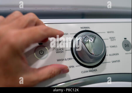 Hand adjusting the controls of a domestic washing machine. Stock Photo