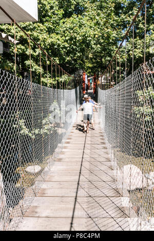 PUERTO VALLARTA, MEXICO - March 10 2018: Tourists walking along the unstable suspension bridge to Isla Rio Cuale from downtown Puerto Vallarta, MX-JAL Stock Photo