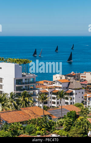 PUERTO VALLARTA, MEXICO - MARCH 10, 2018: A  colorful skyline view of Puerto Vallarta, while  sailboats race, on March 10, 2018. MX-JAL. Stock Photo