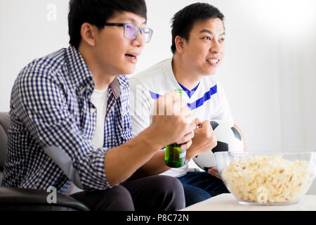 friendship, sports and entertainment concept - happy male friends cheering and watching tv together at home supporting world cup football team win. Stock Photo