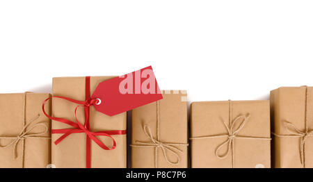 Border of brown paper parcels, one unique with red ribbon bow and gift tag or label, isolated on white background Stock Photo