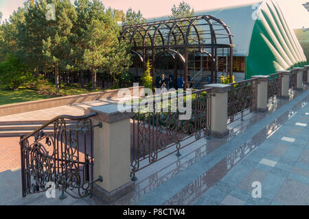 A view from a marble staircase with a curved metal fence and people below standing in front of the alley entrance . For your design Stock Photo