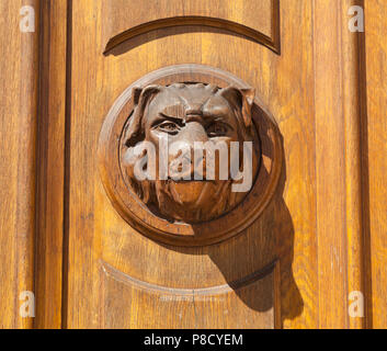 Carved wooden door handle, dogs face, bright sun Stock Photo