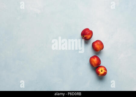 Flat lay of fresh nectarines fruits on light blue background. Top view with copy space. Stock Photo
