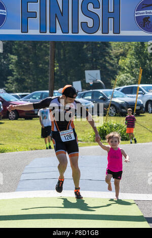 Michael Sikorski wins and crosses the finish line with his daughter at the 2018 Stissing Triathlon Stock Photo