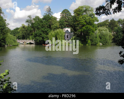 A boat floating on a transparent green lake against a white walking bridge in the distance . For your design Stock Photo