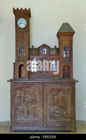 Carved wooden hand-made cabinet made of wood. With beautiful turrets with glasses and clocks. And the pictures on the doors are carved directly on the Stock Photo