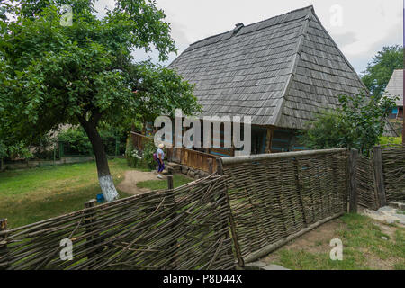A tourist in the courtyard of an old house with a fence gate and wicket made from a vine with interest examines its architecture and arrangement. . Fo Stock Photo