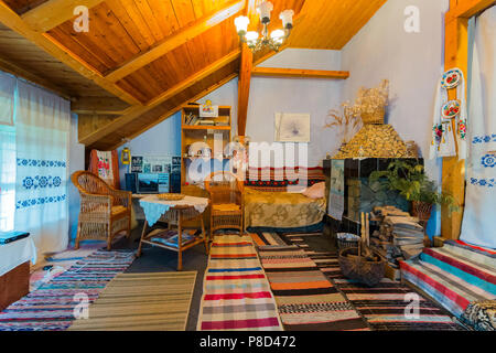 A room with a wooden ceiling with historical objects of everyday life. Woven tracks with patterns rugs furniture made from vines embroidered curtains  Stock Photo