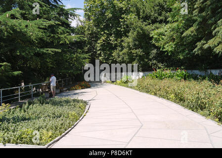 A wide walking alley with flower beds on each side in a cozy park area . For your design Stock Photo