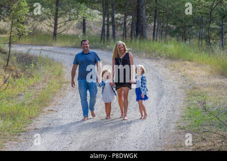 Attractive man and wife, with their 4 and 6 year old daughters, walking down a country dirt road, holding hands, barefoot. Model released-dad #116, gi Stock Photo