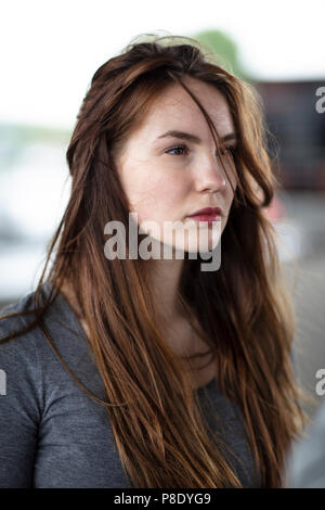 Portrait of the face of a pretty girl standing outdoors. Selective focus. Medium close up. Angle view. Stock Photo