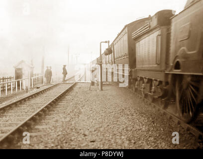 Steam train picking up mail bag, early 1900s Stock Photo