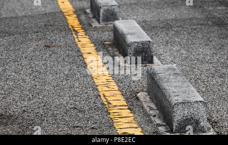 Concrete road side border blocks and yellow dividing line. Close-up photo with selective focus Stock Photo