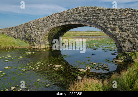 The old arched bridge which crosses the River next to the village of Aberffraw on the Welsh Island of Anglesey Stock Photo