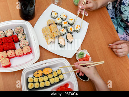 Friends eat Japanese food. Rolls and sushi on the table. Stock Photo