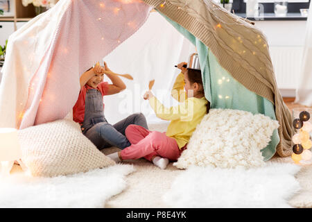 girls with kitchenware playing in tent at home Stock Photo