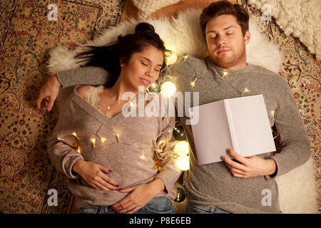 happy couple with garland lying on floor at home Stock Photo