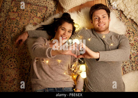 happy couple lying on floor and making hand heart Stock Photo