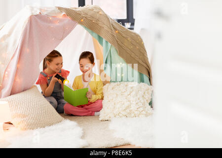 little girls reading book in kids tent at home Stock Photo