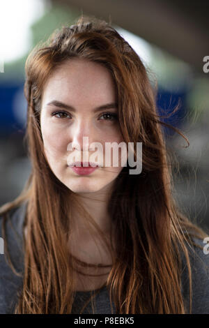 Portrait of the face of a pretty girl standing outdoors and confidently looking at the camera. Selective focus. Medium close up. Stock Photo