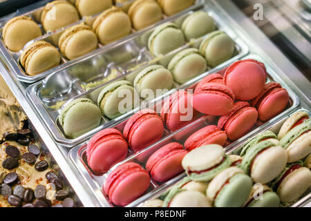 Assortment of colorful macaroons on cafe showcase. Variety of macaron flavours. Sweet almond cakes in store. Stock Photo