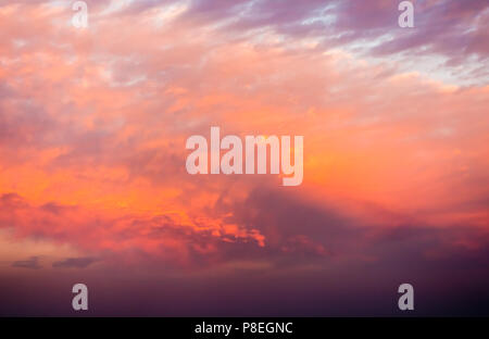 Dramatic dark and cloudy sunset sky in magenta, red, orange and yellow colors. Stock Photo