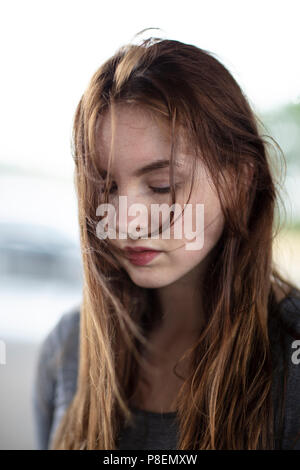 Headshot of a pretty girl looking down with her hair in her face. Medium close up. Selective focus. Stock Photo