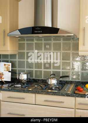 Tiled wall behind saucepans on gas hob in modern kitchen Stock Photo