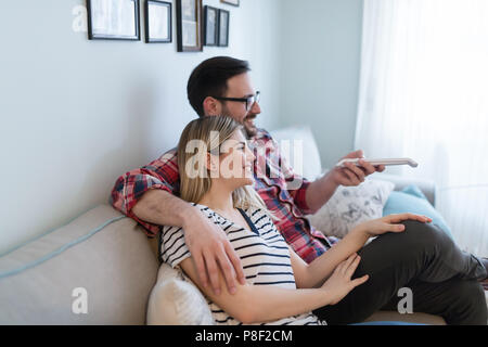 Young happy couple watching tv in living room Stock Photo