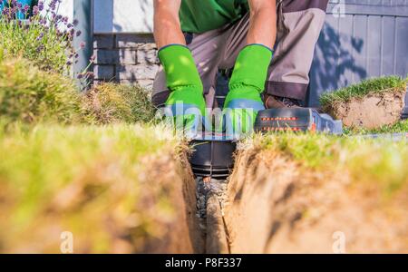 Gardener Building Backyard Garden Watering Systems. Automatic Lawn Sprinklers Installation by Technician. Stock Photo