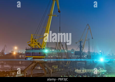 Portal cranes and high-speed hydrofoil ship in night harbor Stock Photo