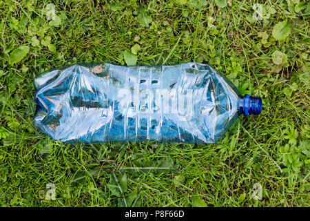 Crushed blue plastic bottle laying in grass. Pollution and environment concept Stock Photo