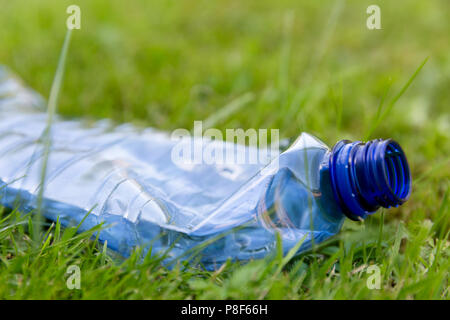 Crushed blue plastic bottle laying in grass. Pollution and environment concept Stock Photo