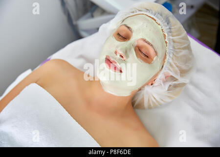 Face peeling mask, spa beauty treatment, skincare. Woman getting facial care by beautician at spa salon, side view, close-up Stock Photo