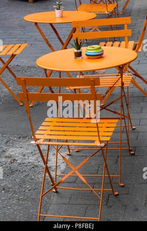 orange painted shabby chic style folding garden tables and chairs. Stock Photo