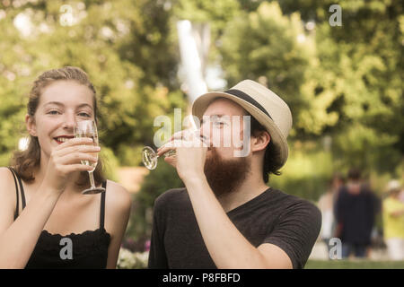 Couple sitting in park making a celebratory toast Stock Photo