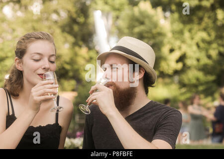 Couple sitting in park making a celebratory toast Stock Photo