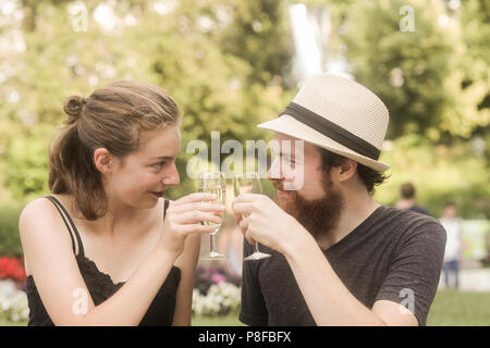 Couple sitting in park making a celebratory toast Stock Photo