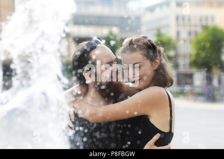 Couple standing by a water fountain hugging Stock Photo