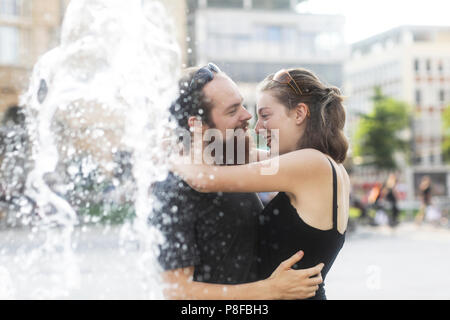 Couple standing by a water fountain hugging Stock Photo