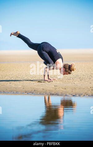 Woman doing a lifted half crow yoga pose, The Strait Natural Park, Tarifa, Cadiz, Andalusia, Spain Stock Photo