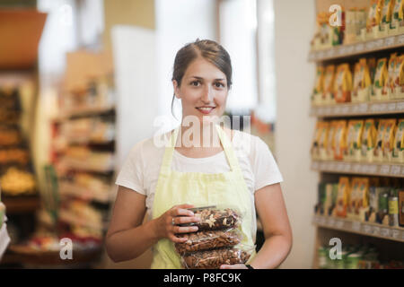 Smiling sales assistant holding bags of nuts Stock Photo