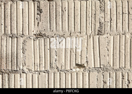 Old damaged brickwork from corrugated concrete blocks, abstract texture for backdrop. Stock Photo
