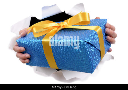Man hands delivering or giving small gift through torn white paper background Stock Photo