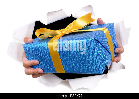 Man hands delivering or giving gift through torn white paper background Stock Photo