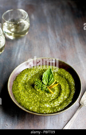 Lemon Basil Pesto served with bread, walnuts and white wine. Photographed on a mixed brown background. Stock Photo
